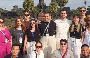 Topdeck tour group posing for a photo in front of the famous Angkor Wat temple in Cambodia, known for being the largest religious structure in the world.