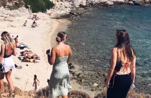 Topdeck tour group going down a hilly path to a secluded beach in Greece during their sailing trip.