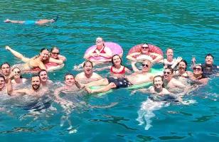 Topdeck tour group posing for a photo while swimming in the crystal blue waters of Turkey.