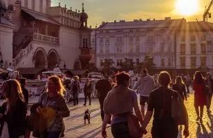 People and horse drawn carriages enjoy Krakow's old city streets as the sun sets.