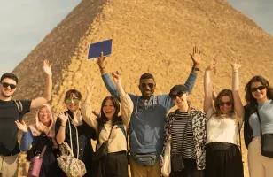 A group of Topdeck travellers pose for a photo in front of one the iconic Pyramids of Egypt.