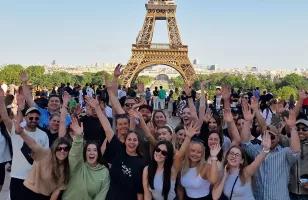 Topdeck tour group smiling and posing for a group photo in front of the famous Eiffel Tower of Paris.