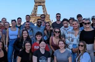 Topdeck tour group taking a photo together in front of the famous Eiffel Tower of Paris during their Get Social: Mega European trip