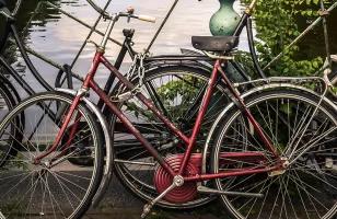 A lone bike leaning on the railing of a road looking out over one of the canals in Amsterdam.