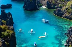 An aerial view of 4 Boats and two platforms are moored off the crystal blue waters of Palawan Island in the Phillipines.