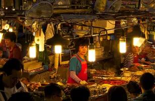 People selling and purchasing various foods and ingredients at Gwanjang Market, the oldest and one of the largest traditional markets in South Korea.