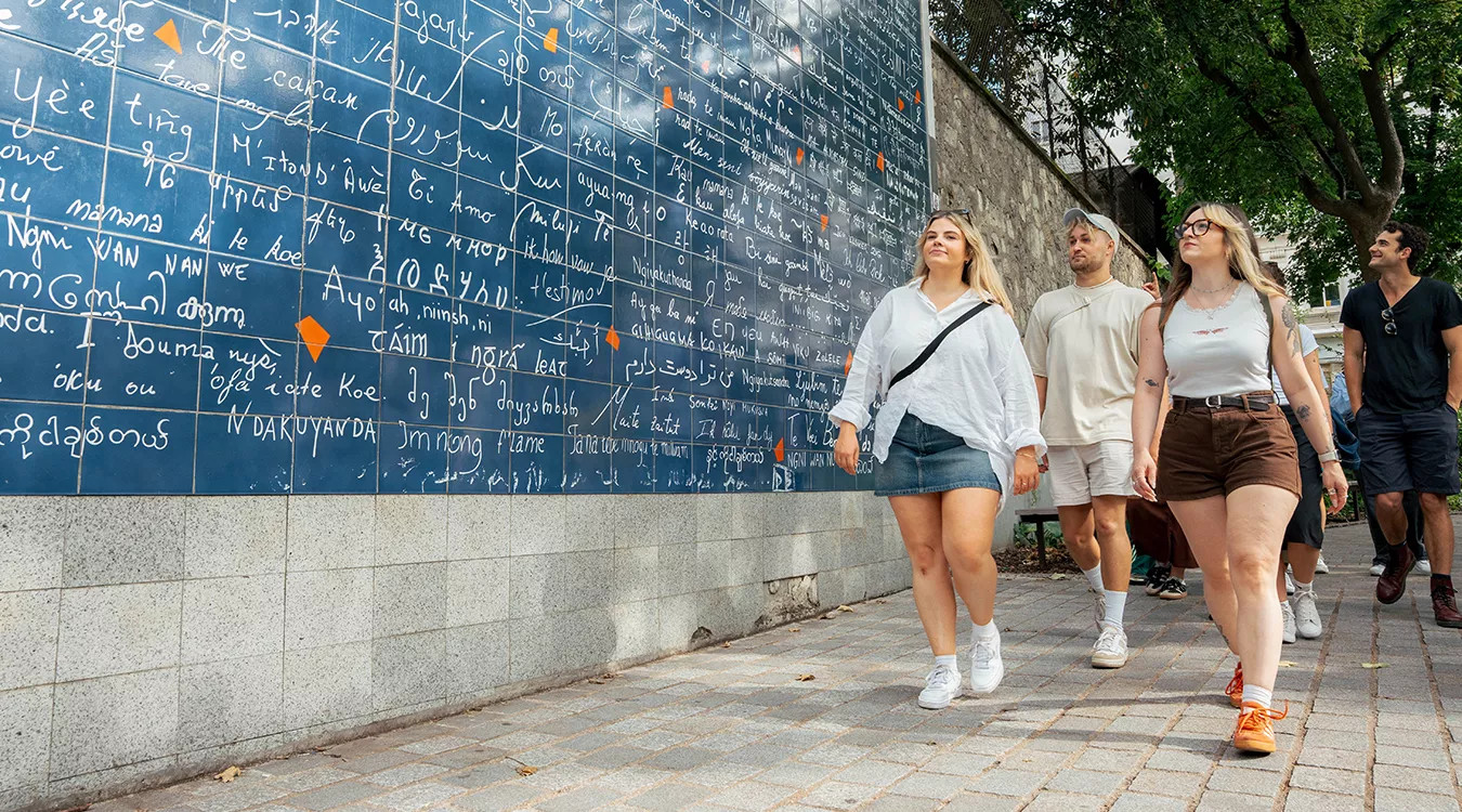 People walking past the The Wall of Love in Montmartre, Paris.