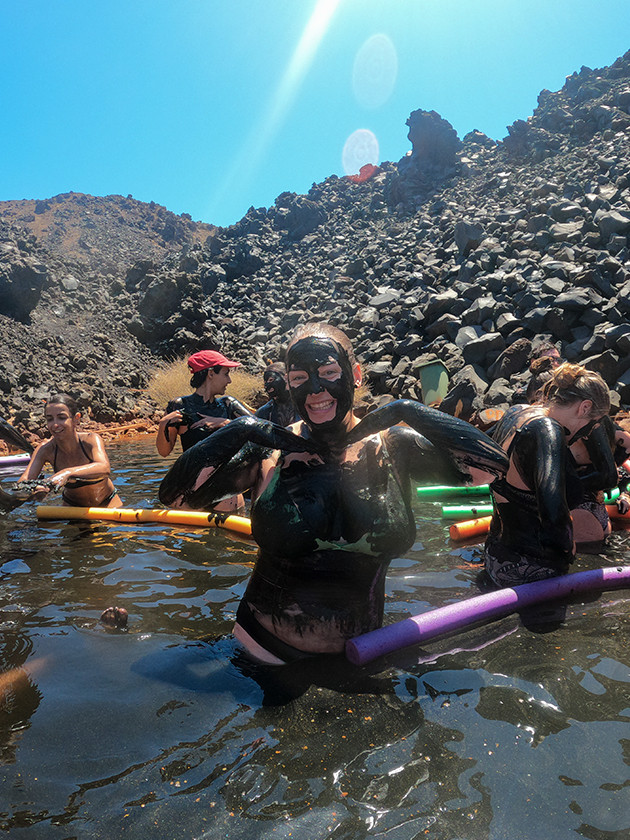 Topdeck travelers taking a mud bath near Santorini Volcano in Greece.