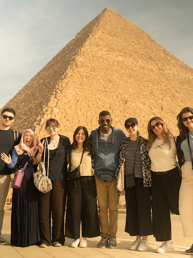 Topdeckers taking a group photo together in front of one of the Great Pyramids of Egypt.