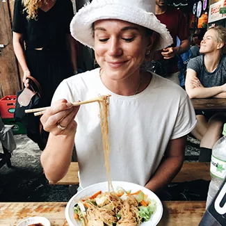 Person lifting noodles from their bowl with chopsticks.