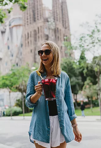 Person standing in front of the Sagrada Familia holding a jug of sangria.