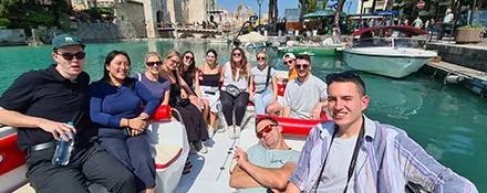 A Topdeck Tour group taking a group selfie while sailing around the clear blue waters around a fort.