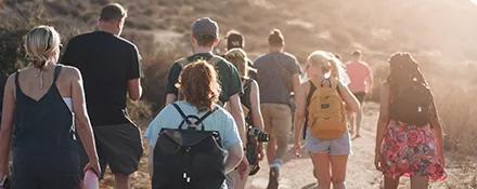 A group of Topdeck travelers hiking as the sun begins to set.